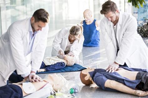 Doctors Undertaking Cardiopulmonary Resuscitation Training On Dummies