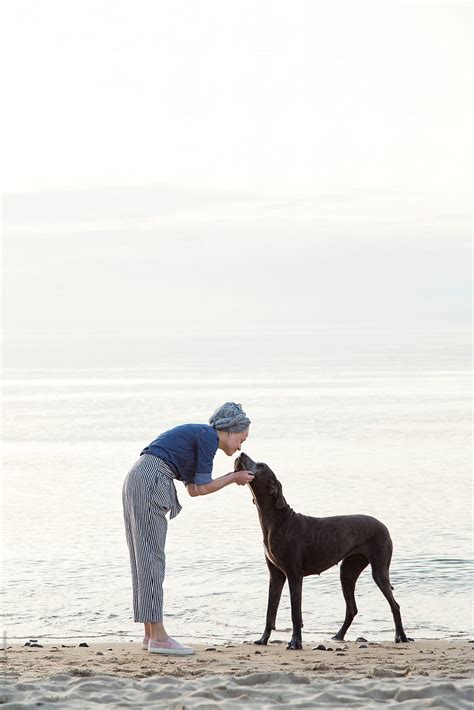 Woman Stroking Dog On Shore By Stocksy Contributor Danil Nevsky