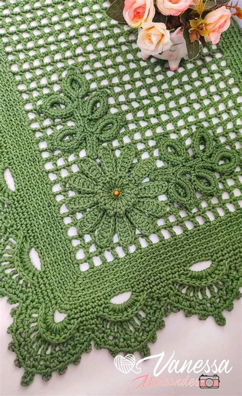 A Green Crocheted Tablecloth With Flowers On It And A Bouquet Of Roses