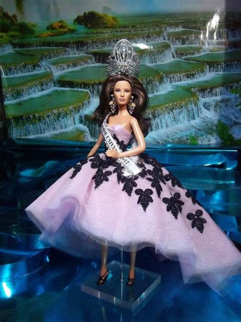 a barbie doll wearing a pink dress and tiara in front of a waterfall scene