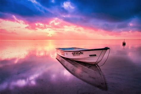 Boat Reflected In The Sea At Sunset