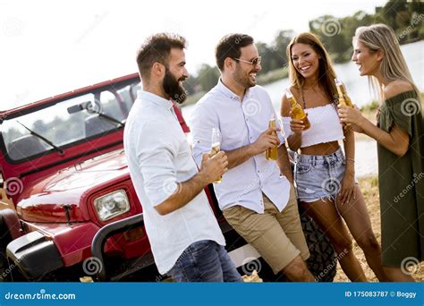 Group Of Young People Drinking And Having Fun By Car Outdoor Stock