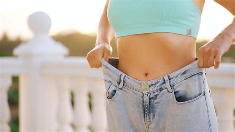 mulher apreciar peso perda às lar fêmea dentro velho jeans depois de bem sucedido dieta
