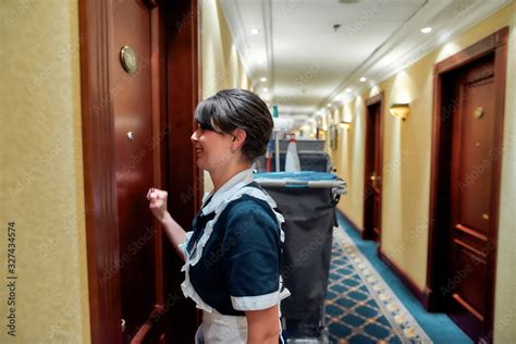 Let Us Clean Smiling Hotel Maid In Uniform Knocking On The Door For Room Service While Standing