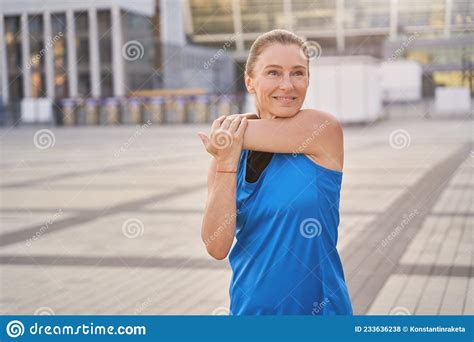 Portrait Of Attractive Middle Aged Woman In Sportswear Stretching Her