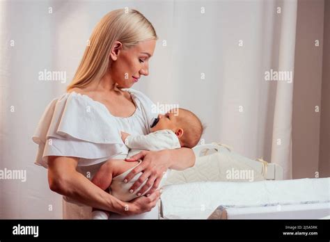 Caucasian Mother Applying Baby Powder Before Putting Diapers On Her Four Month Old Baby In Bed
