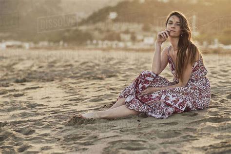Happy Brunette Woman Sitting In The Beach At Golden Hour Stock Photo Dissolve