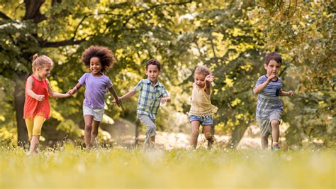 Small Happy Kids Having Fun While Running In Nature Stock Photo