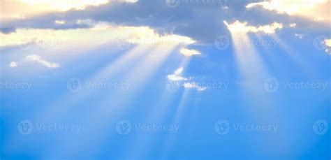 The Suns Rays Break Through The Blue Clouds The Background Of The Sky