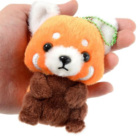 A Hand Holding A Small Stuffed Animal In Its Right Hand And Wearing A