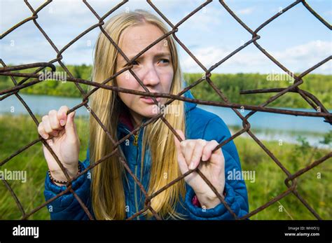 Young Woman Looking Through Chainlink Fence Stock Photo Alamy