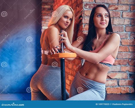Two Sporty Girls Dressed In Sportswear With Barbells Posing In A Stock