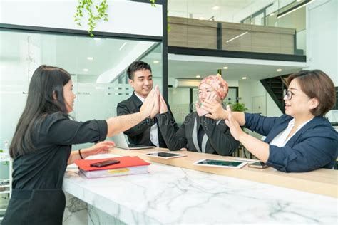Business Colleagues Giving Each Other High Five In The Office Stock