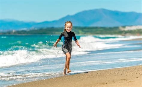 girl in a wetsuit running along the beach stock image image of lifestyles cheerful 169569453