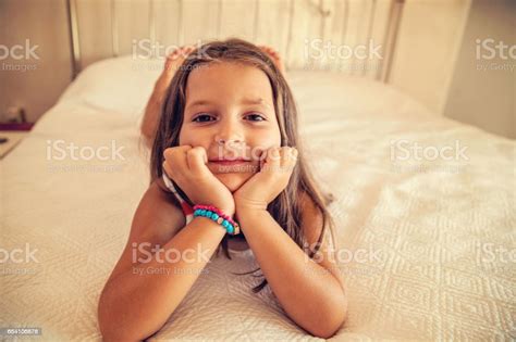 Cute Little Girl Lying Down On Bed Looking At Camera Stock Photo