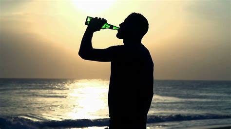 It becomes tough to choose any one. Man drinking beer on the beach during sunset, steadycam ...