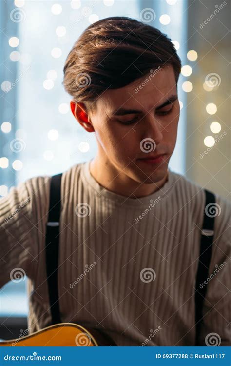 Young Man Sitting At Home And Playing Guitar Dramatic Stock Photo