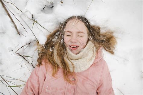 Cute Young Girl Having Fun On A Walk In Snow Covered Park On Chilly