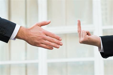 Businessman Showing Middle Finger To Partner Offering Handshake Stock