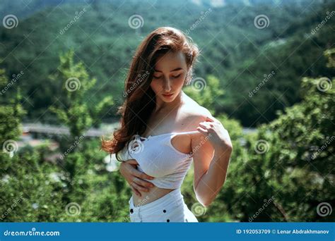 A Girl In A White Tank Top Slightly Takes Off Her Clothes In The Forest