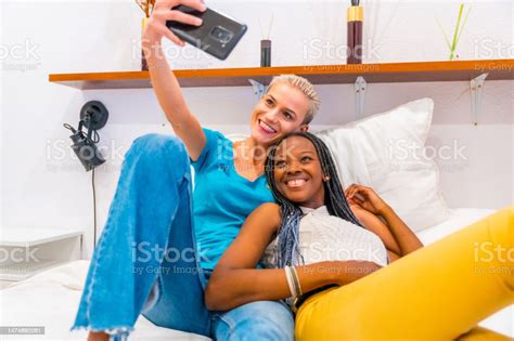 schönes lesbisches paar das auf dem bett liegt und zu hause ein selfie macht lgbtkonzept