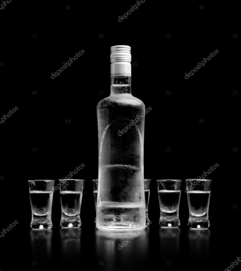 Bottle And Glasses Of Vodka Standing Isolated On Black Background