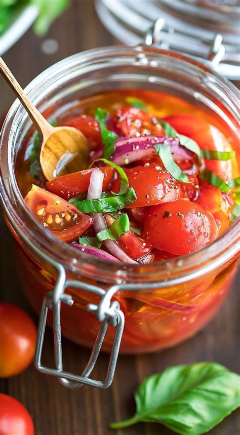 A Glass Jar Filled With Tomato Salad On Top Of A Wooden Table Next To