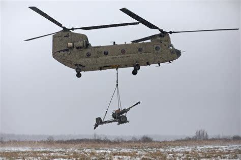 An Army Ch 47 Chinook Helicopter Takes Off Carrying A Howitzer At Fort