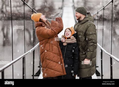 La Joven Madre El Padre Y La Hija Pequeña Coge Copos De Nieve En Un