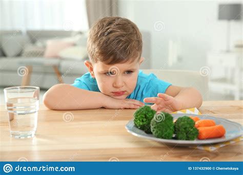 Unhappy Little Boy Refusing To Eat Vegetables At Table Stock Photo