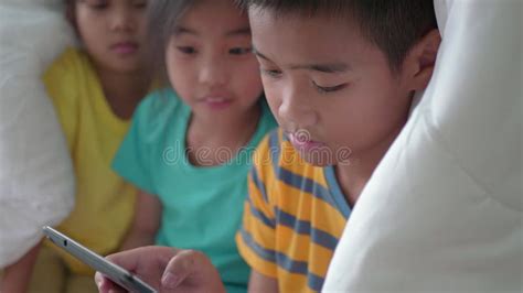 Children S Brother And Sister Using Tablet Under The Blanket On The Bed