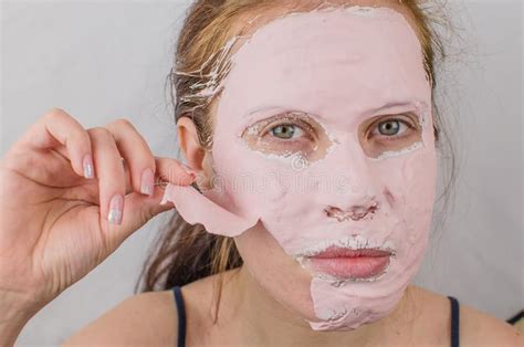 Good Looking Woman Having A Face Mask On Half Of Her Face Against Plain