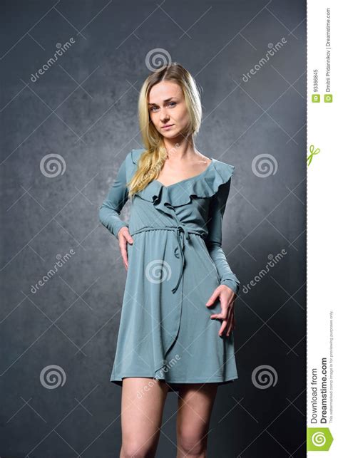 Skinny Blonde Girl In Gray Dress On The Background Of Gray Wall Stock