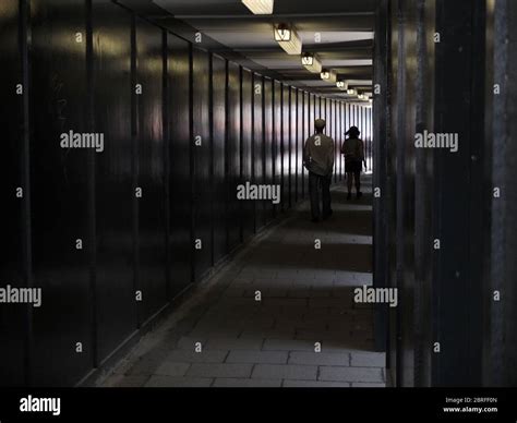 Two People Walk Through A Covered Walkway Tunnel Running Alongside A