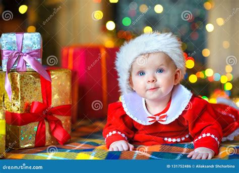 Little Baby In Santa Claus Costume Lies On The Floor Near Ts Stock