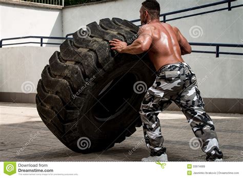 A Muscular Man Participating In A Cross Fit Workout By Doing A Tire