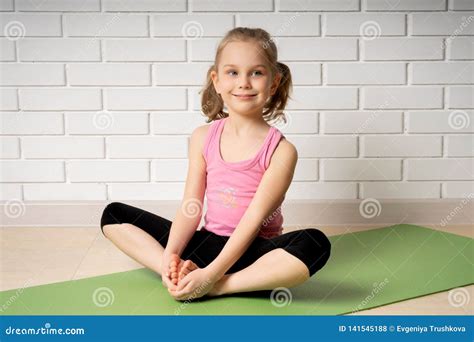 Cheerful Little Girl Doing Sports Exercises On The Mat At Home