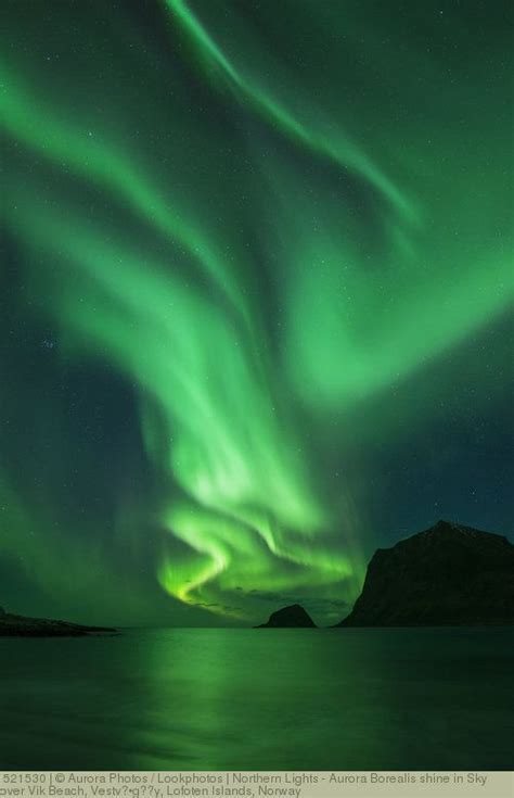 The Aurora Bore Is Glowing Green In The Night Sky Over Water With