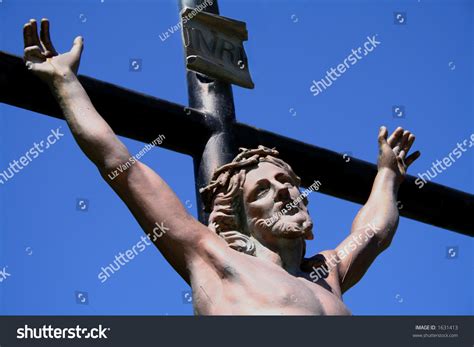 Realistic Statue Of Christ On The Cross Against Blue Sky Stock Photo
