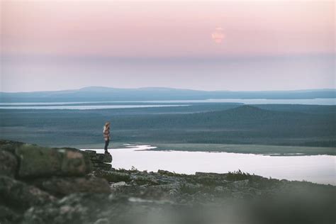 A Person Standing On Top Of A Rocky Hill Next To A Body Of Water With