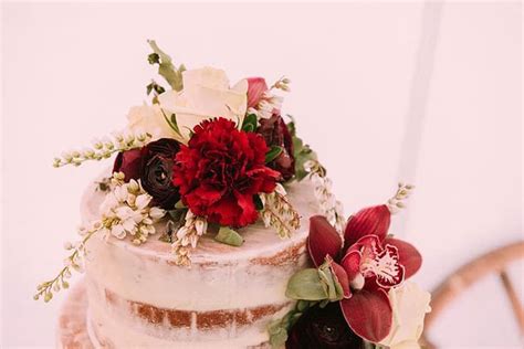 A Wedding Cake With Red And White Flowers On Top
