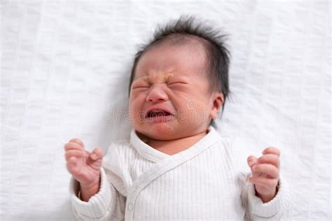 Crying And Angry Newborn Baby Boy Lying On White Bed At Homeinfant