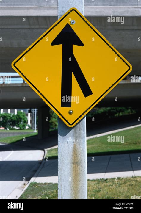 A Yellow And Black Diamond Shaped Merging Traffic Road Sign On A Thick