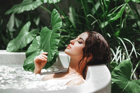 Woman Relaxing In Round Outdoor Bath With Tropical Flowers