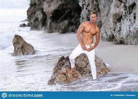 Fitness Male Model In White Pants And Shirtless Posing On Tropical