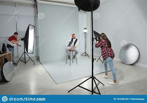 Professional Photographer With Assistant Taking Picture Of Young Man In