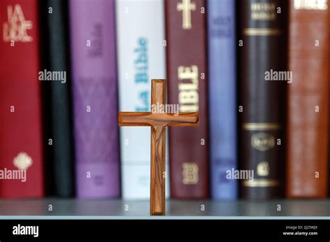 Wooden Cross And Christian Bibles Of Different Versions On A Bookshelf