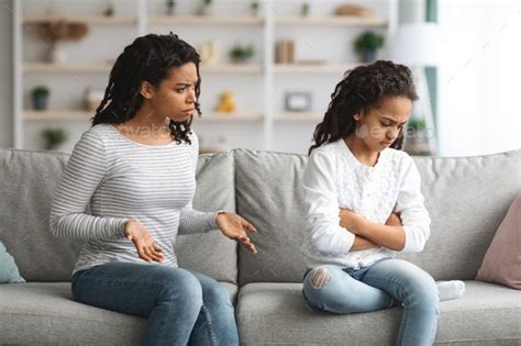 Angry Mother Scolding Daughter Sitting On Couch At Home Stock Photo By