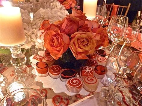 An Arrangement Of Cupcakes And Roses On A Table With Candles In The