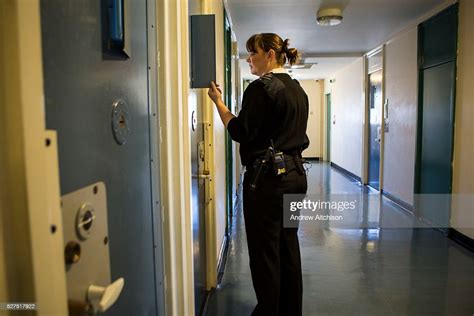 A Female Prison Officer Checks On A Prisoner Through The Door Window